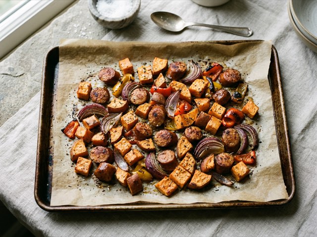 Roasted chicken sausage rounds and caramelized sweet potato cubes on a sheet pan with smoked paprika.
